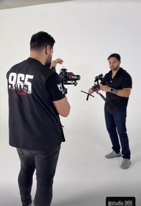 Camera crew with gimbals on the white cyclorama at Studio 965, with the studio logo and tag visible